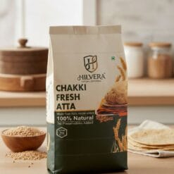 Premium Hilvera Chakki Fresh Atta Packaging With 100% Natural And Preservative-Free Whole Wheat Flour, Showing Soft Rotis And Wheat Stalks On A Rustic Wooden Table.